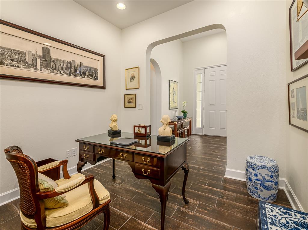 A home office features a dark wood desk, a patterned chair, and tile flooring — 4521 BARLETTA COURT, WESLEY CHAPEL, FL