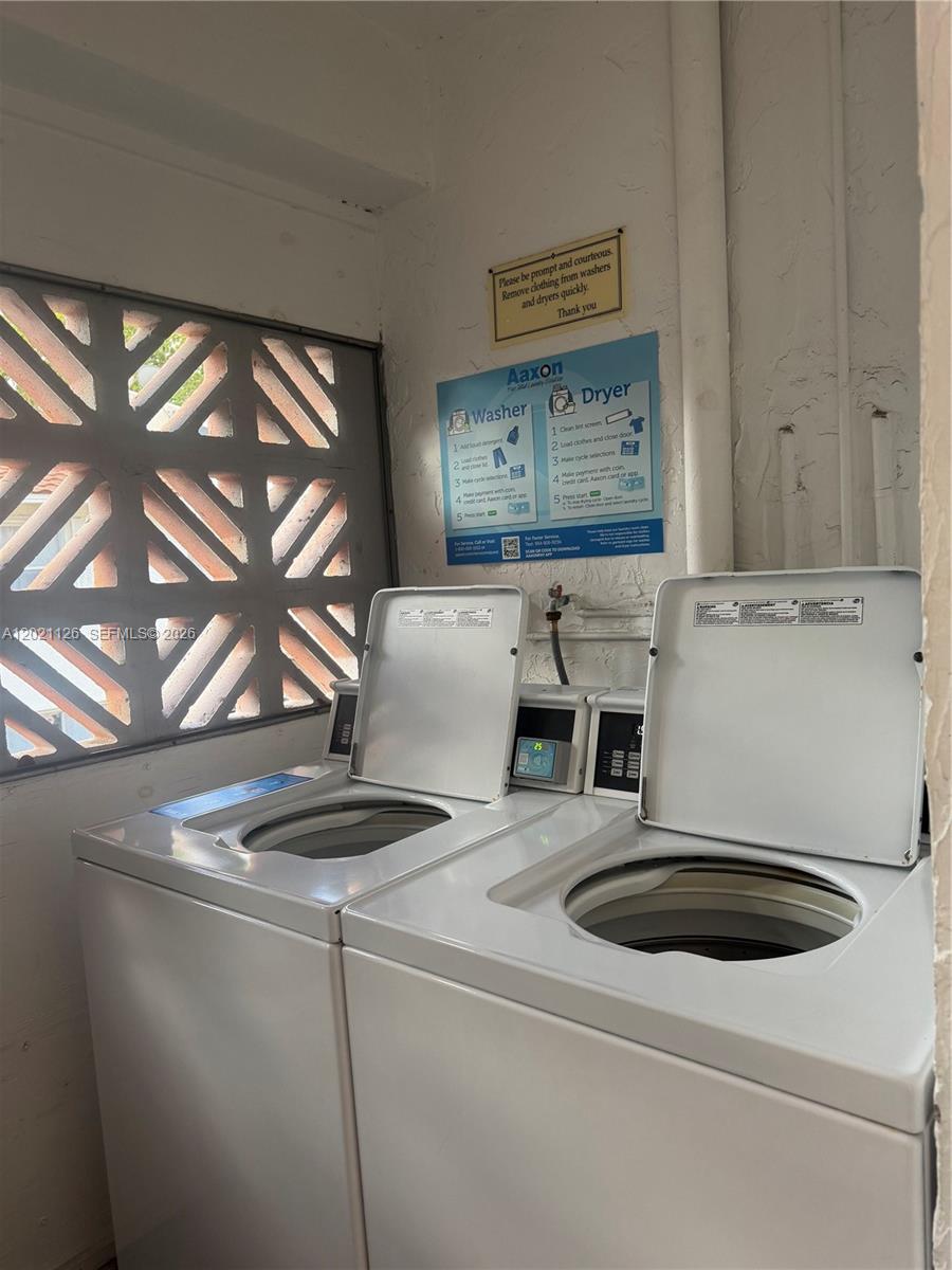 A laundry room contains two white top-loading washing machines beneath a set of instructional signs — 7610 Stirling Rd # 205G, Davie FL 33024, DAVIE, FL