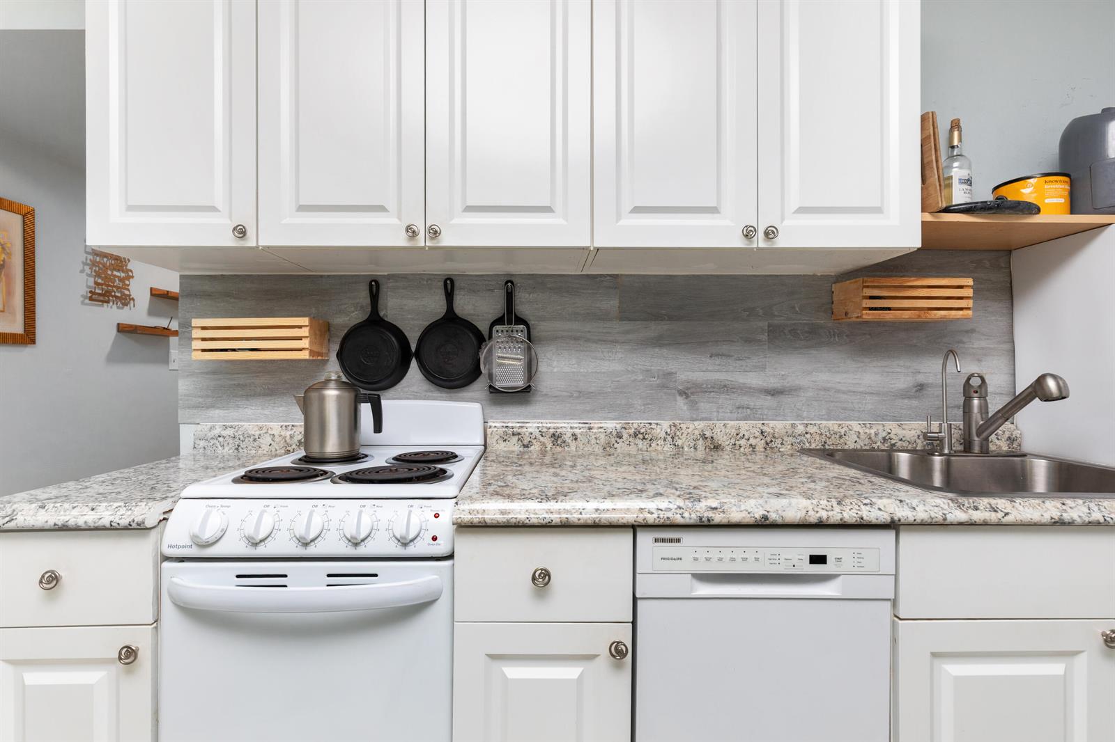 A kitchen features white cabinets, a speckled granite countertop, a white stove, and a dishwasher — 505 NE 20th Avenue # 112, Deerfield Beach FL 33441, DEERFIELD BEACH, FL