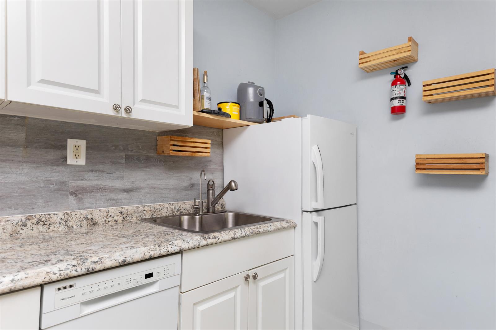 A kitchen features white cabinets, a granite countertop, a stainless steel sink, and a refrigerator — 505 NE 20th Avenue # 112, Deerfield Beach FL 33441, DEERFIELD BEACH, FL
