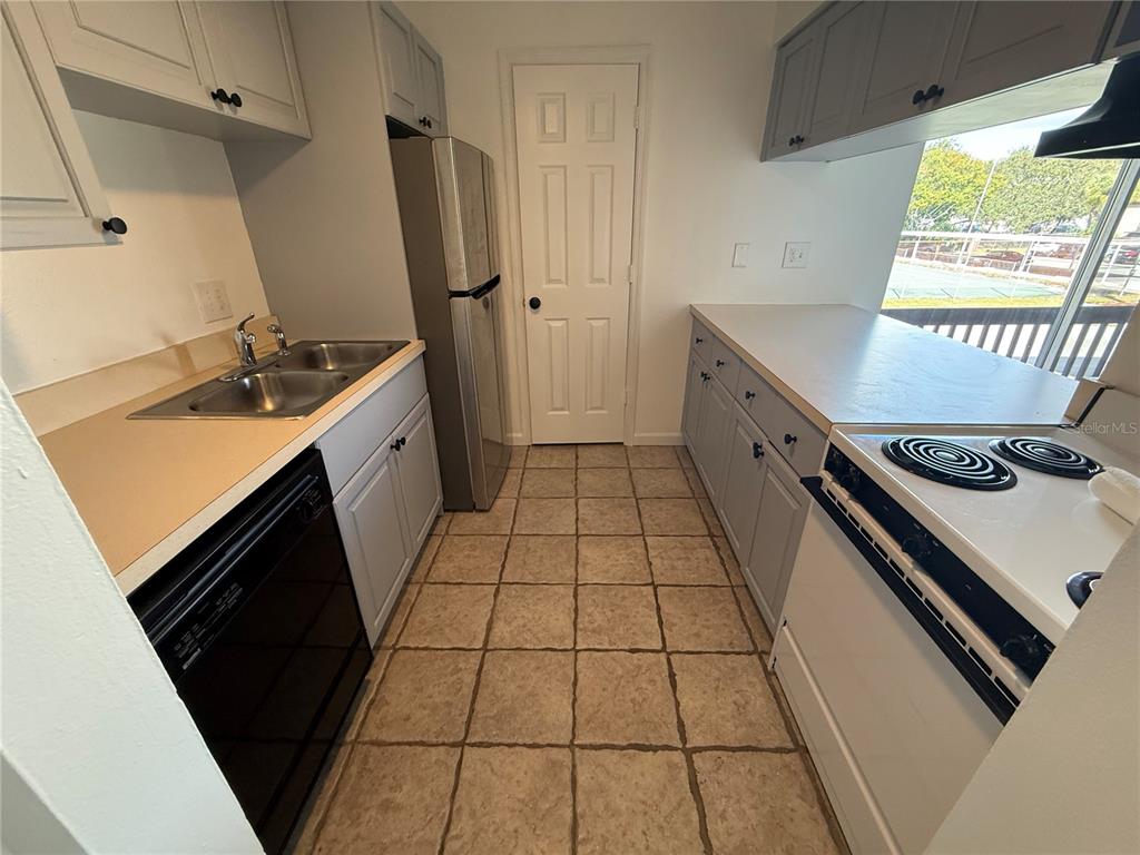 A kitchen features light gray cabinets, a black dishwasher, a white stove, and tile flooring — 2636 HIDDEN LAKE DRIVE N UNIT H, SARASOTA, FL