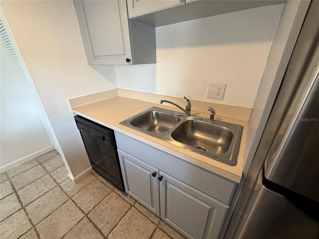 A kitchen features gray cabinets, a double-basin stainless steel sink, and a black dishwasher — 2636 HIDDEN LAKE DRIVE N UNIT H, SARASOTA, FL