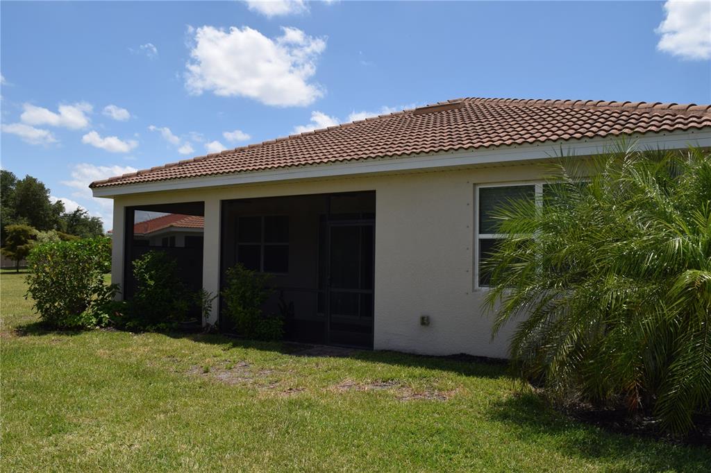 The exterior of a house features a screened-in patio, a tiled roof, and landscaping — 24376 RIVERFRONT DRIVE, PUNTA GORDA, FL