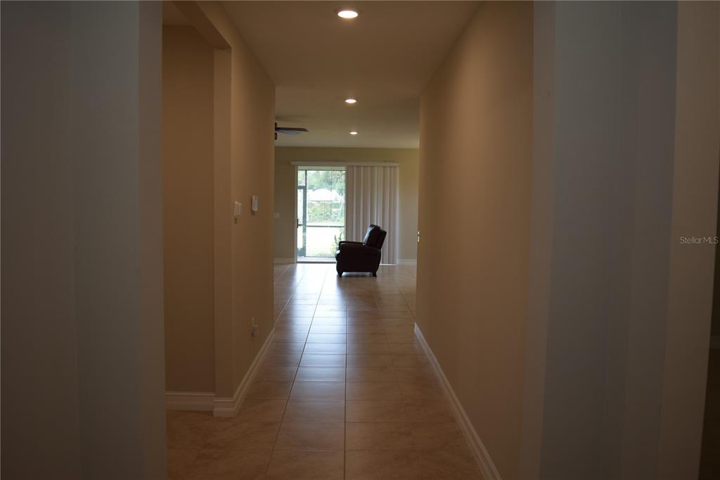 A tiled hallway leads to a living area with a sliding glass door and recliner — 24376 RIVERFRONT DRIVE, PUNTA GORDA, FL