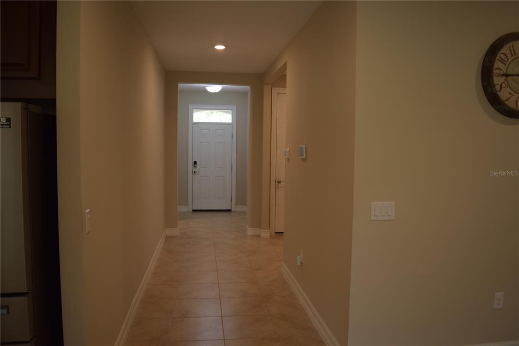 A hallway with tile flooring leads to a white front door with a transom window — 24376 RIVERFRONT DRIVE, PUNTA GORDA, FL