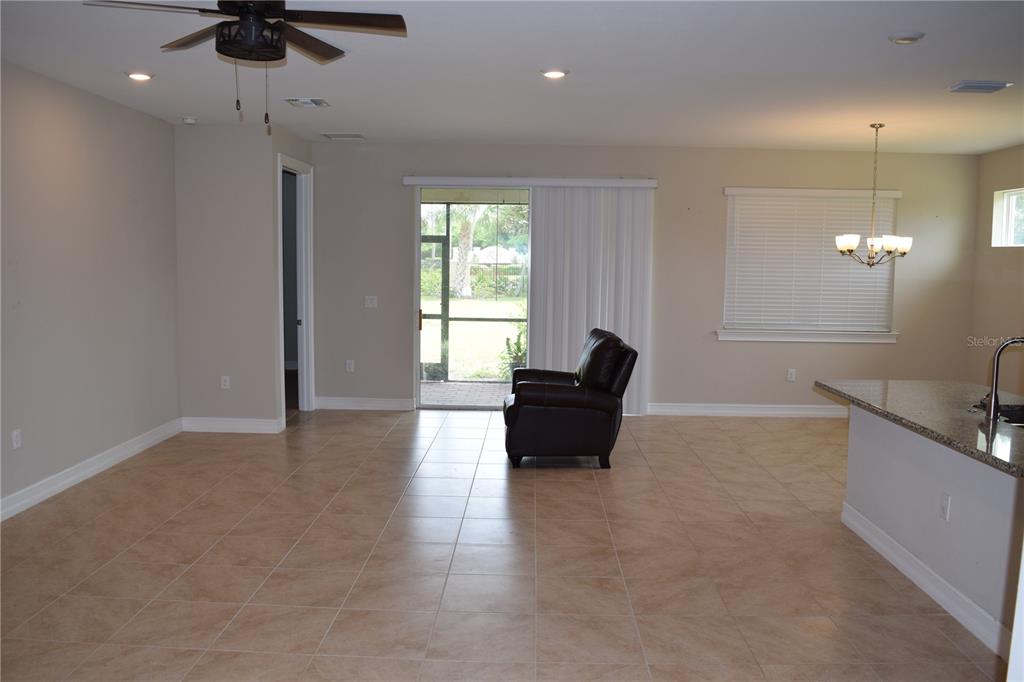 A spacious living room with tile flooring, a ceiling fan, and a sliding glass door — 24376 RIVERFRONT DRIVE, PUNTA GORDA, FL