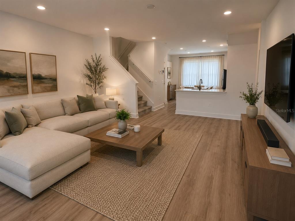 A living room features a sectional sofa, wooden coffee table, and stairs leading to another level — 15038 GROVESIDE ROAD, WINTER GARDEN, FL