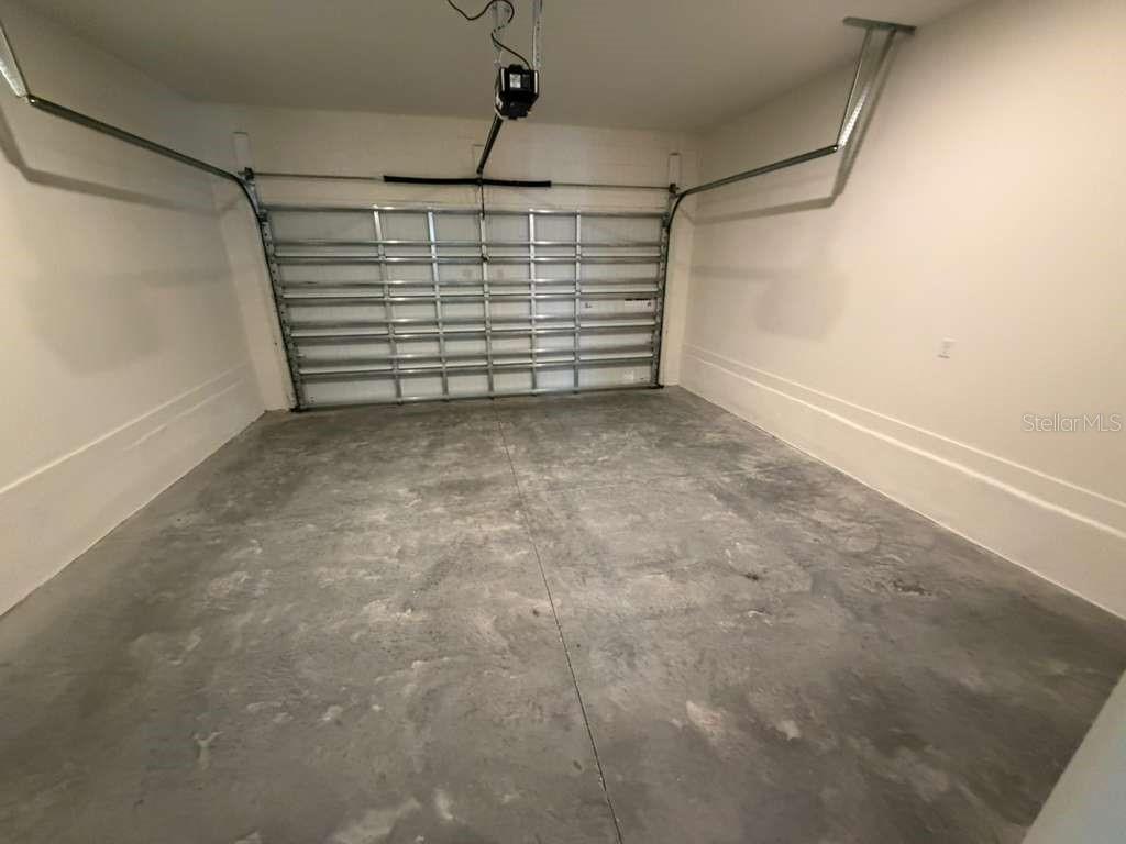 An empty garage with a concrete floor, white walls, and a metal sectional door — 15038 GROVESIDE ROAD, WINTER GARDEN, FL