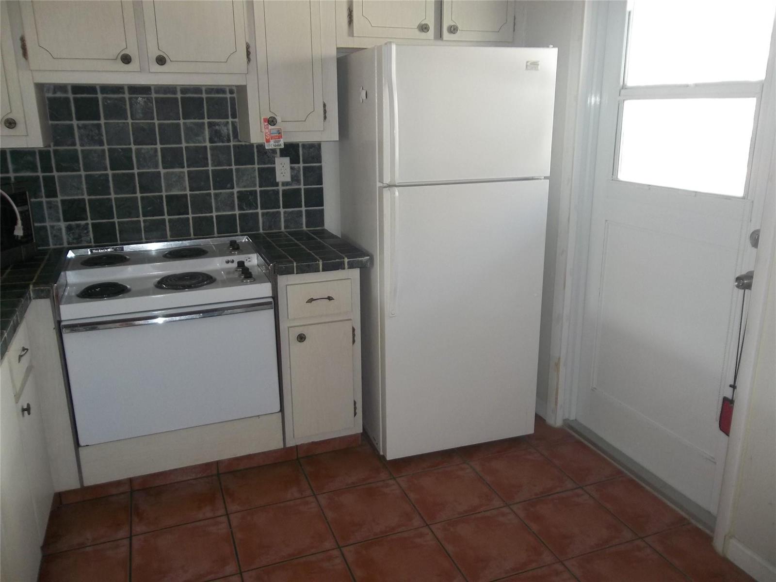 A kitchen features white cabinets, a white stove, a white refrigerator, and dark tiled countertops — 1893 S Ocean Drive # 302, Hallandale Beach FL 33009, HALLANDALE BEACH, FL