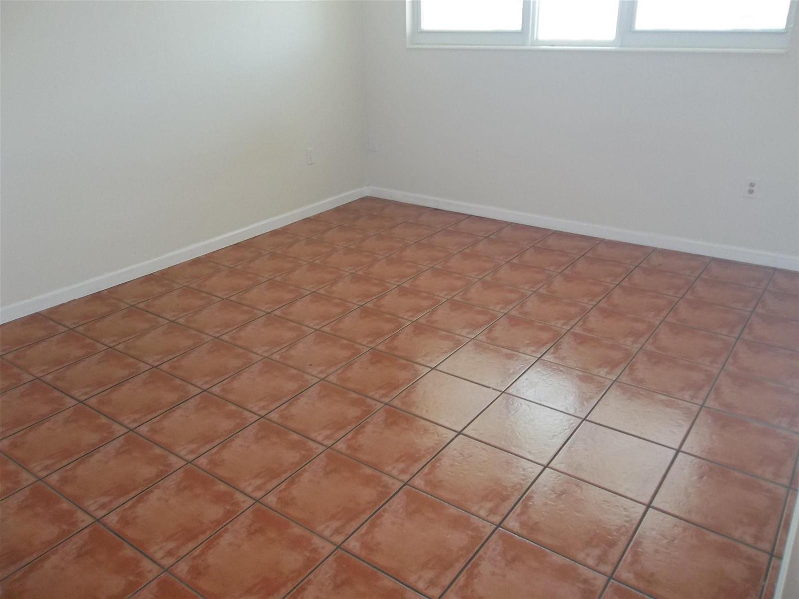 An empty room features white walls, a window, and brown square floor tiles — 1893 S Ocean Drive # 302, Hallandale Beach FL 33009, HALLANDALE BEACH, FL