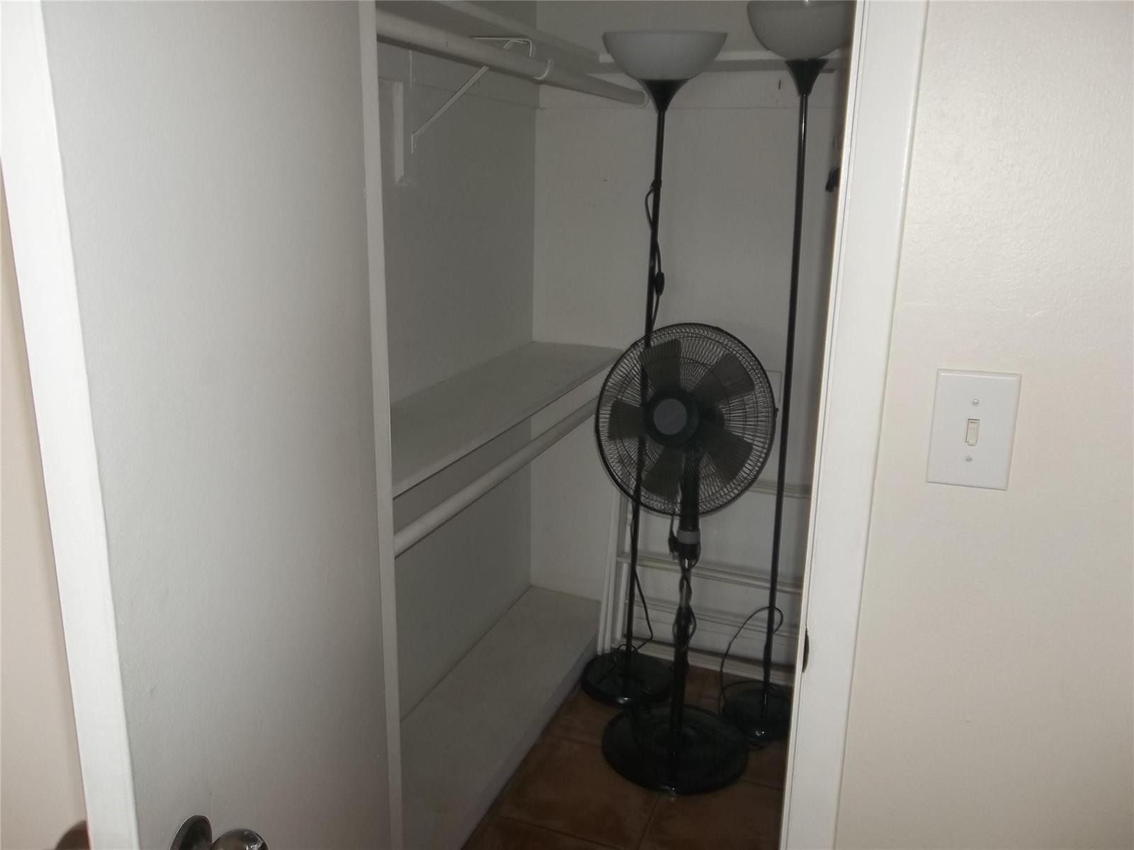 A small closet with white shelving, a hanging rod, and two floor lamps and a fan — 1893 S Ocean Drive # 302, Hallandale Beach FL 33009, HALLANDALE BEACH, FL