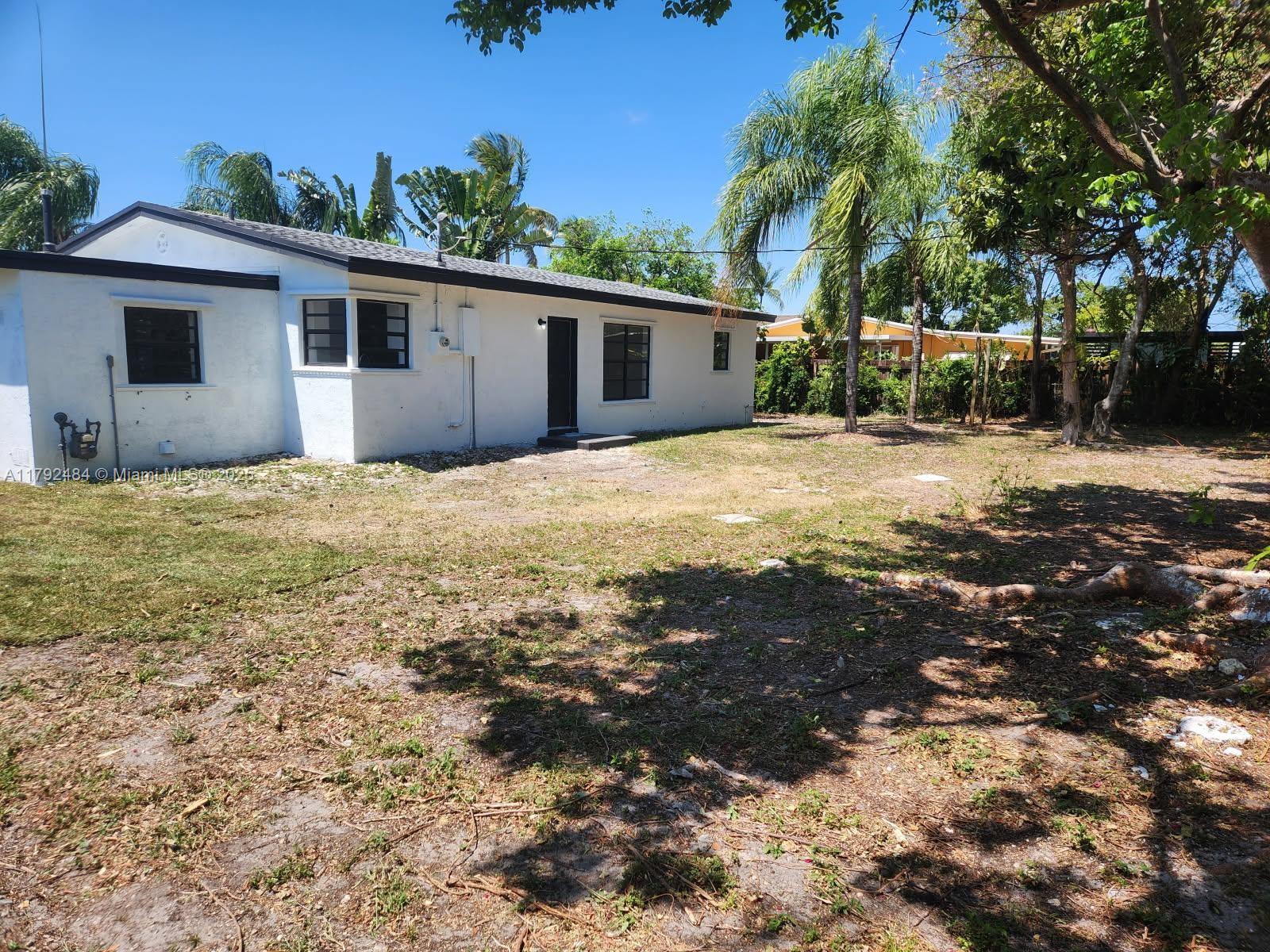 A white single-story house with a dark roof stands on a large, grassy lot — 9340 Martinique Dr, Cutler Bay FL 33189, CUTLER BAY, FL
