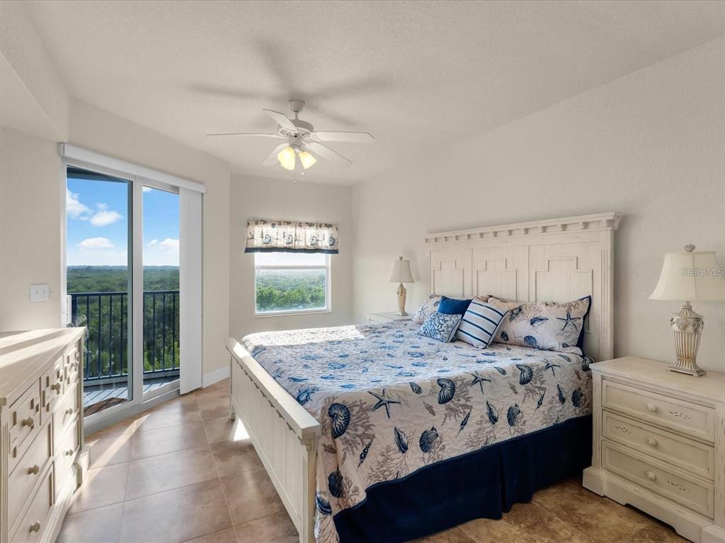 A bedroom features a king bed with coastal bedding, a ceiling fan, and a balcony door — 5300 SOUTH ATLANTIC AVENUE UNIT 19406, NEW SMYRNA BEACH, FL