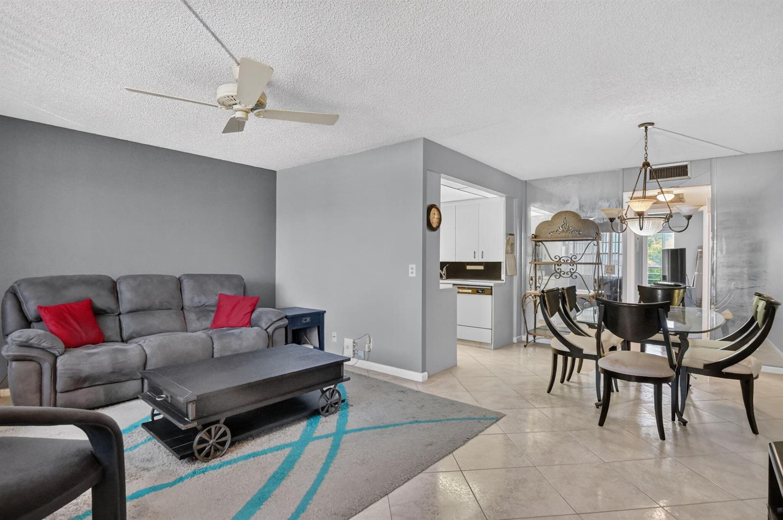 A living room with a grey sofa and coffee table opens to a dining area — 3090 Wolverton E, Boca Raton FL 33434, BOCA RATON, FL