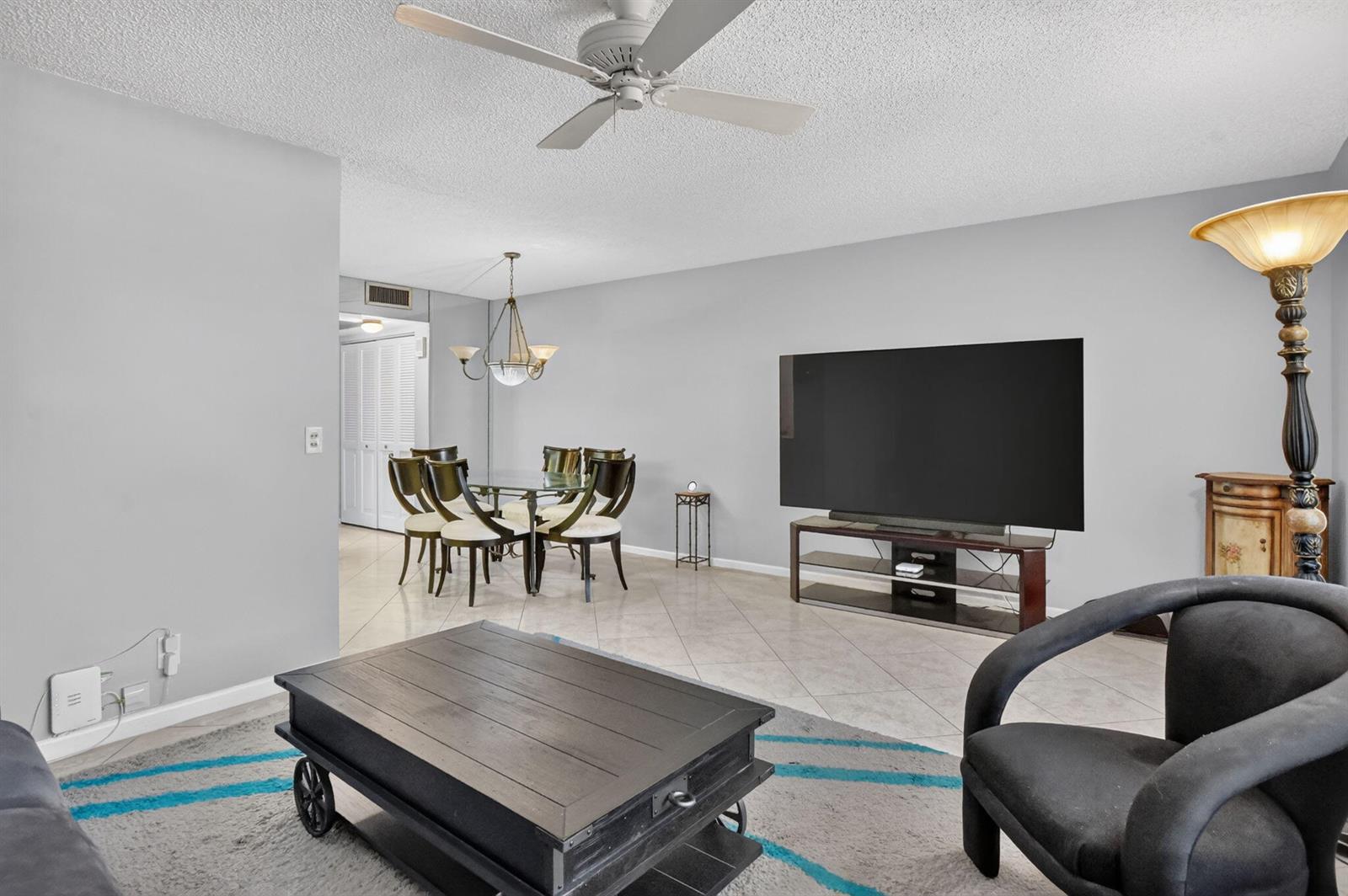 A living room and dining area feature tile flooring, a ceiling fan, and a television — 3090 Wolverton E, Boca Raton FL 33434, BOCA RATON, FL