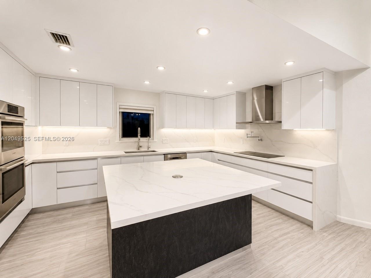 A modern kitchen features white flat-panel cabinets, a large marble-topped island, and stainless steel appliances — 2616 Oakbrook Ct, Weston FL 33332, WESTON, FL