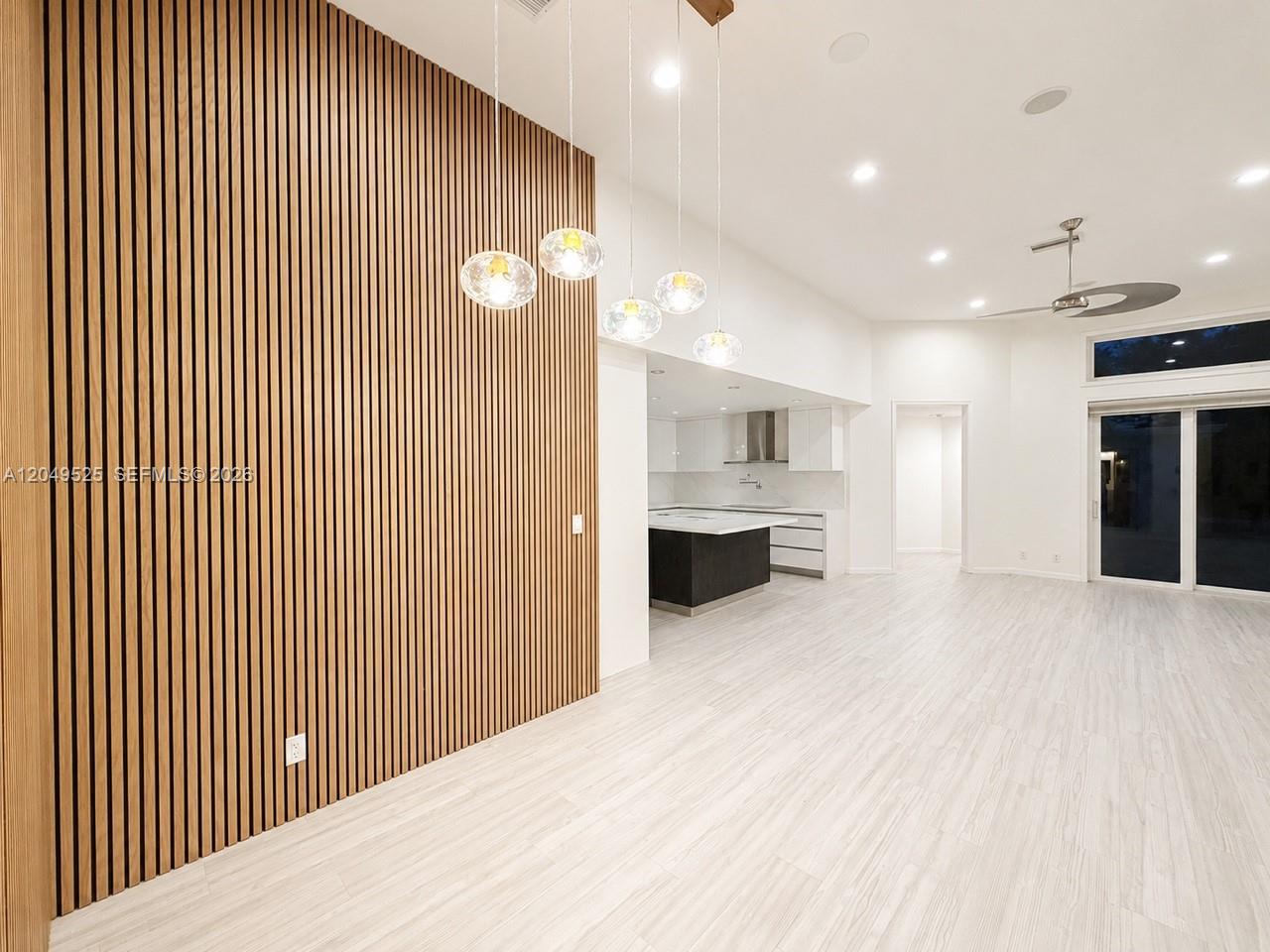 A modern living area features a wood-slat accent wall, pendant lighting, and light-colored flooring — 2616 Oakbrook Ct, Weston FL 33332, WESTON, FL