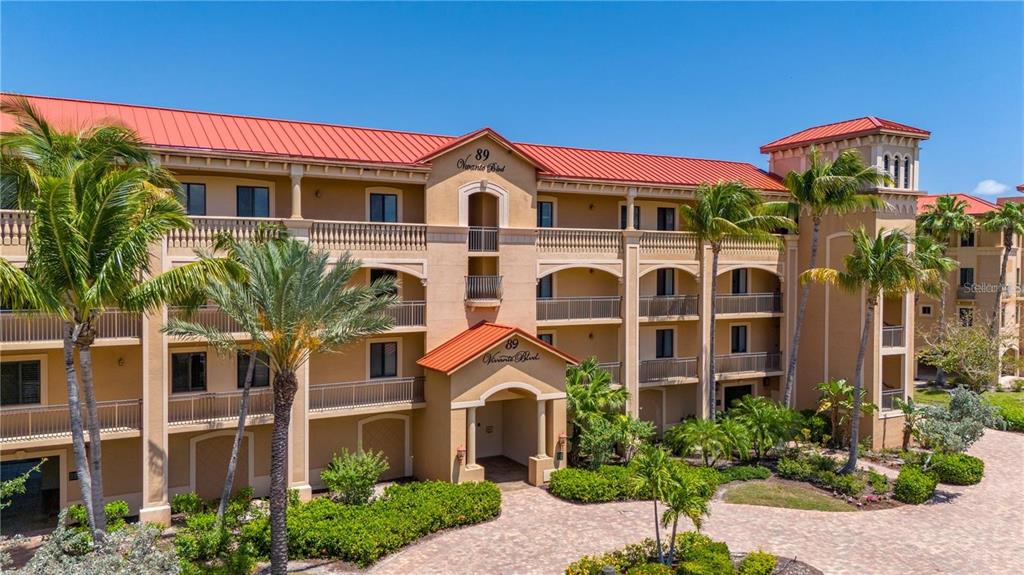 A three-story apartment building with a red metal roof and beige stucco exterior — 89 VIVANTE BOULEVARD UNIT 203, PUNTA GORDA, FL