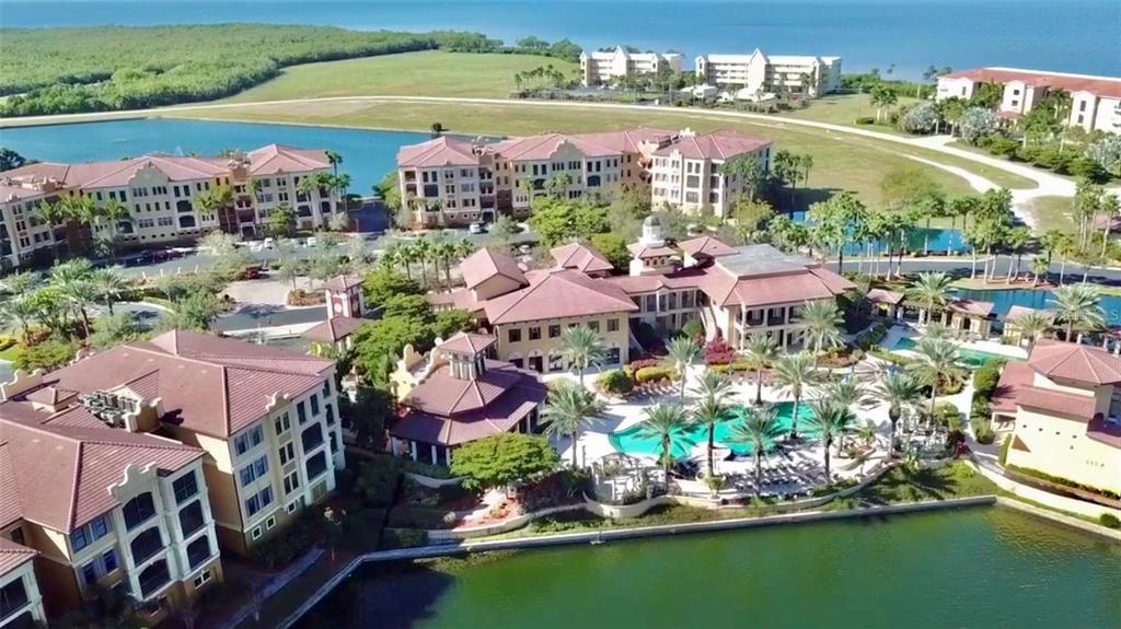 An aerial view shows a resort complex with multiple buildings, a swimming pool, and lakes — 89 VIVANTE BOULEVARD UNIT 203, PUNTA GORDA, FL