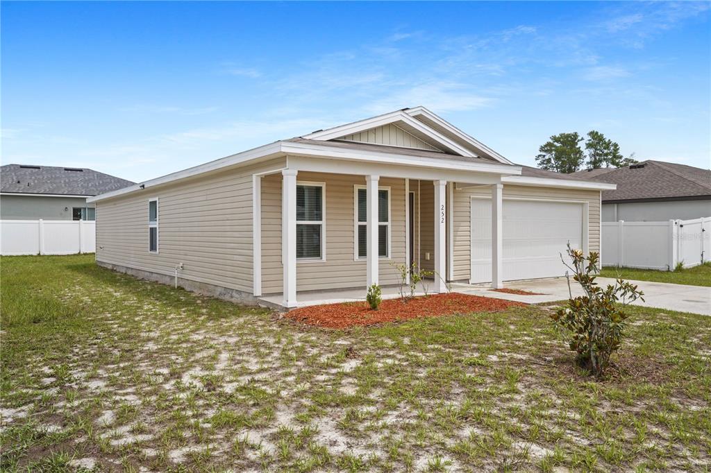 A single-story house with beige siding, a covered front porch, and an attached two-car garage — 252 FIG COURT, KISSIMMEE, FL