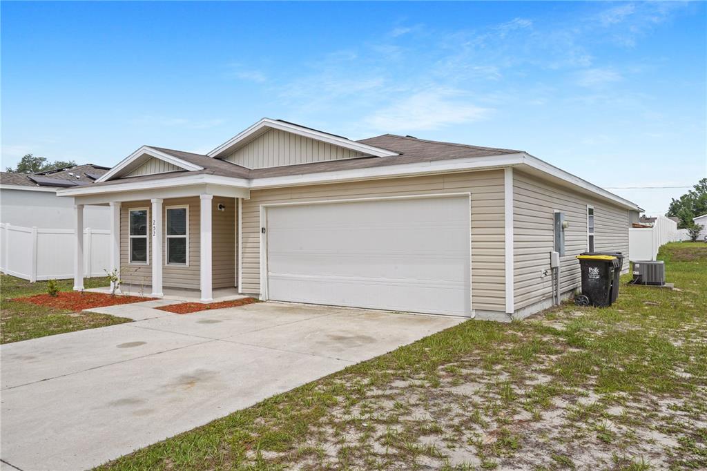 A single-story house with beige vinyl siding, a two-car garage, and a covered front porch — 252 FIG COURT, KISSIMMEE, FL