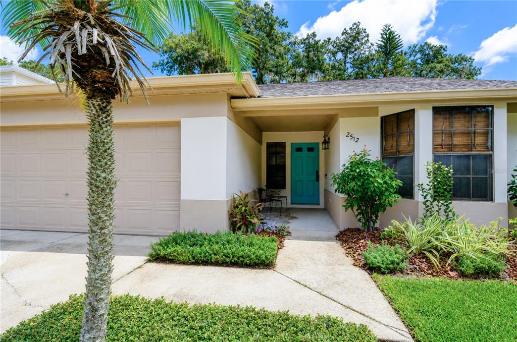 A single-story house exterior features a beige facade, a teal front door, and a palm tree — 2512 WRENCREST CIRCLE, VALRICO, FL