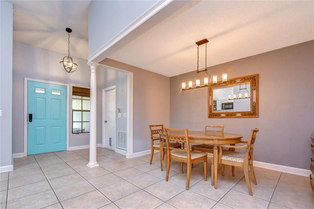 A dining area with a wooden table, chairs, a chandelier, and a light blue door — 2512 WRENCREST CIRCLE, VALRICO, FL