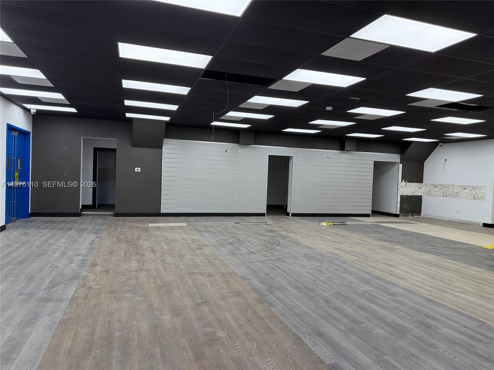 An empty commercial space features a black drop ceiling, recessed lighting, and wood-look flooring — 1201 E University Ave, Gainesville FL 32641, GAINESVILLE, FL