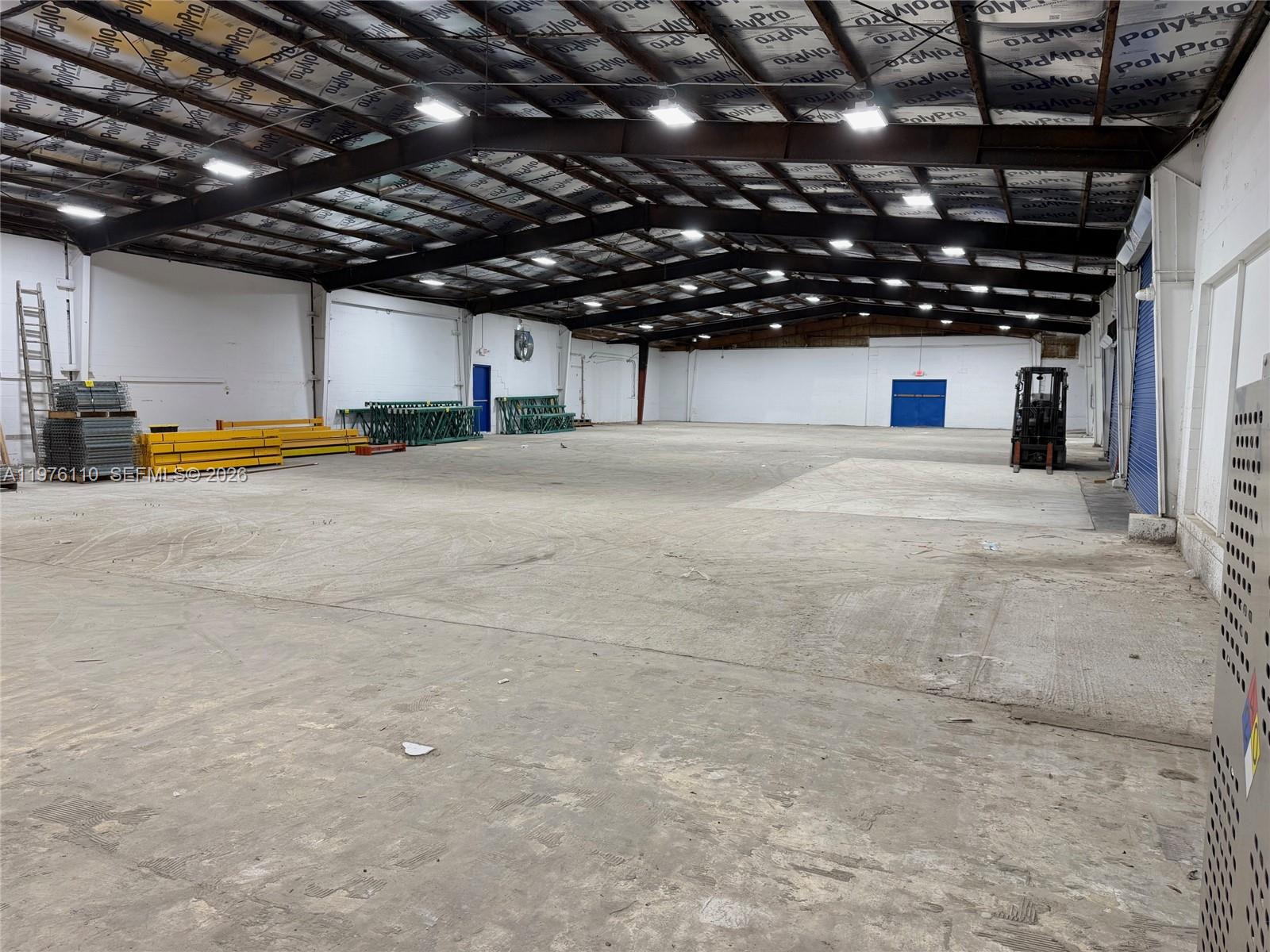 An expansive, empty warehouse space features a concrete floor, exposed metal ceiling, and overhead lighting — 1201 E University Ave, Gainesville FL 32641, GAINESVILLE, FL