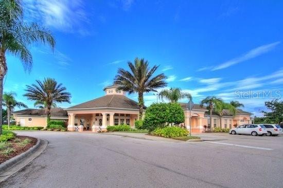 A beige community clubhouse with a circular roof and palm trees under a blue sky — 8110 PRINCESS PALM LANE, KISSIMMEE, FL