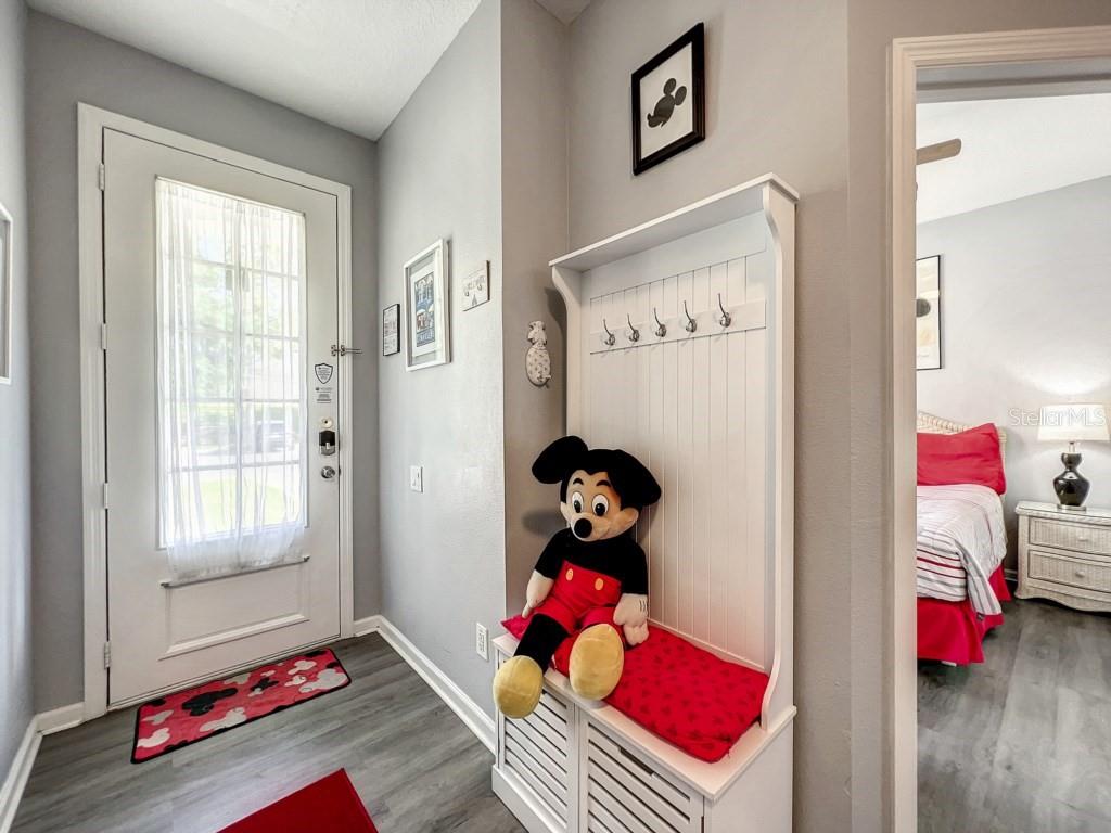An entryway features a white hall tree with a Mickey Mouse plush and grey flooring — 8110 PRINCESS PALM LANE, KISSIMMEE, FL