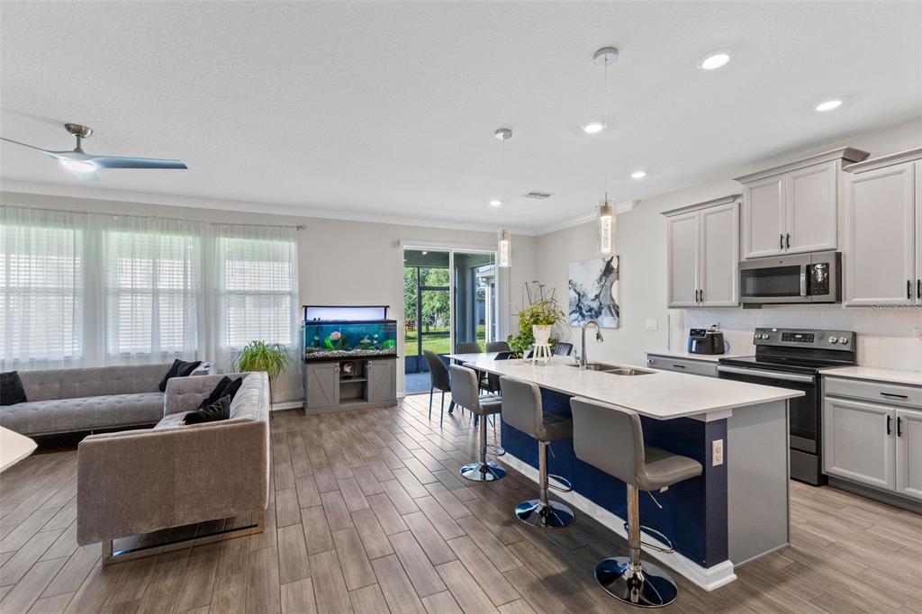 A kitchen with a blue island and gray cabinets opens into a living area — 5311 AMERSHAM LANE, ST CLOUD, FL