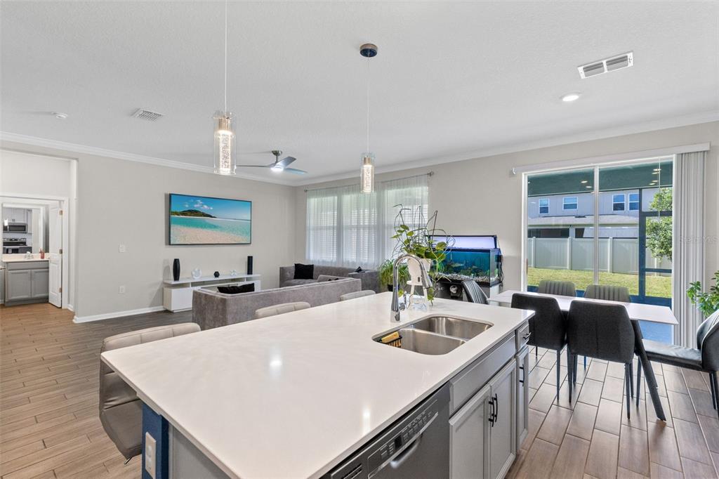 A kitchen island with a double sink overlooks an open-concept living and dining area — 5311 AMERSHAM LANE, ST CLOUD, FL
