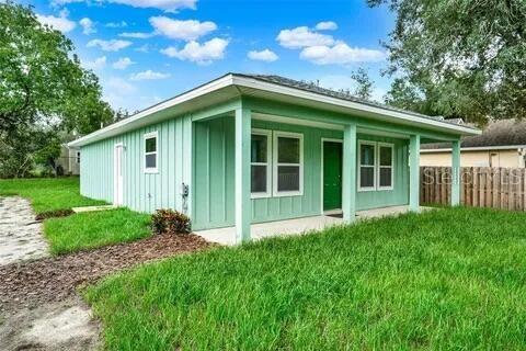 A light green, single-story house with a covered front porch and a wooden fence — 40091 OAKRIDGE DRIVE, LADY LAKE, FL