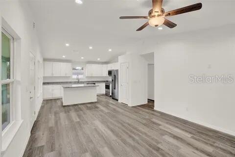 An open-concept kitchen and living area features white cabinetry, a center island, and wood-look flooring — 40091 OAKRIDGE DRIVE, LADY LAKE, FL