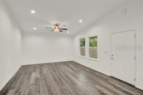 An empty room with white walls, gray wood-look flooring, a ceiling fan, and a door — 40091 OAKRIDGE DRIVE, LADY LAKE, FL