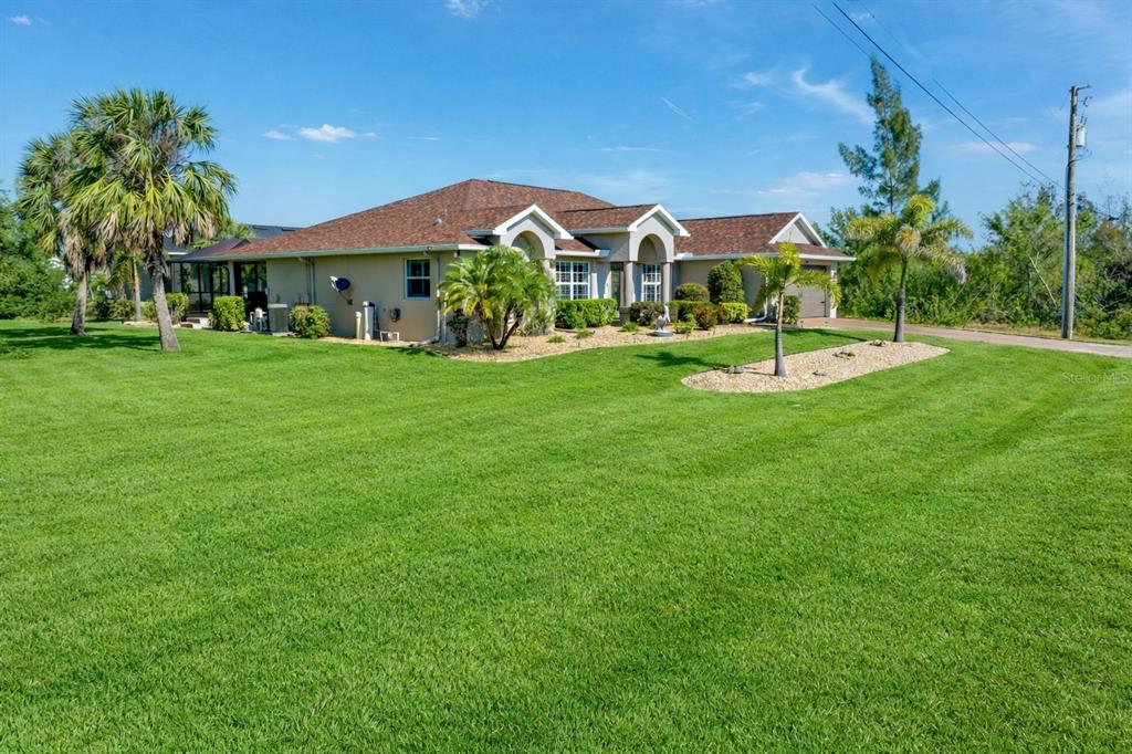 A single-story house with a brown shingled roof, tan stucco exterior, and a two-car garage — 8251 ARLEWOOD CIRCLE, PORT CHARLOTTE, FL