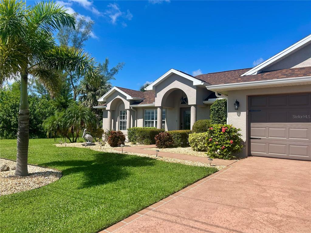 A single-story house with a brown shingled roof sits on a large, grassy lawn — 8251 ARLEWOOD CIRCLE, PORT CHARLOTTE, FL