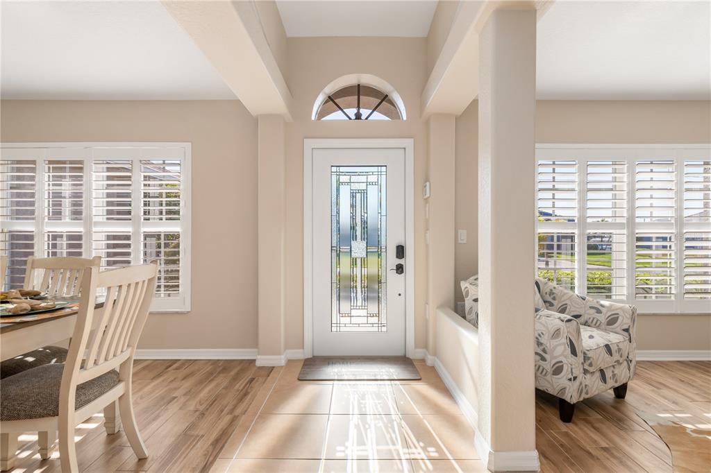An entryway with tile flooring leads to an open living room with a sectional sofa — 8251 ARLEWOOD CIRCLE, PORT CHARLOTTE, FL