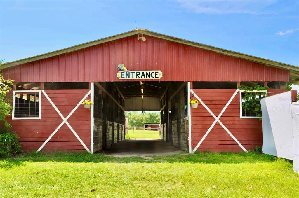 A red barn with an open center aisle and an entrance sign above the doorway — 11150 W HIGHWAY 40, OCALA, FL