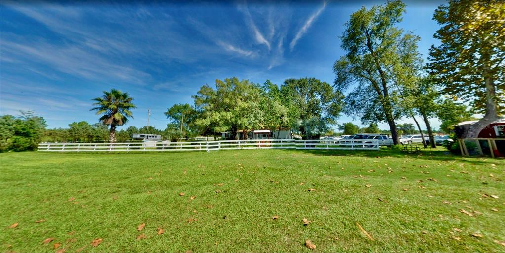 A white fence encloses a grassy yard with trees and a house in the background — 11150 W HIGHWAY 40, OCALA, FL