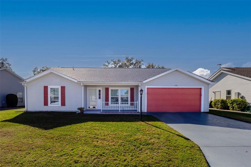 A single-story house with light gray siding, a red garage door, and red window shutters — 25049 NAVEL AVENUE, LEESBURG, FL