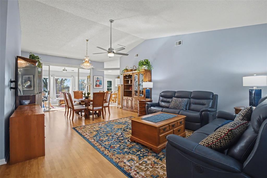A living room and dining area with hardwood floors, a blue rug, and leather furniture — 25049 NAVEL AVENUE, LEESBURG, FL