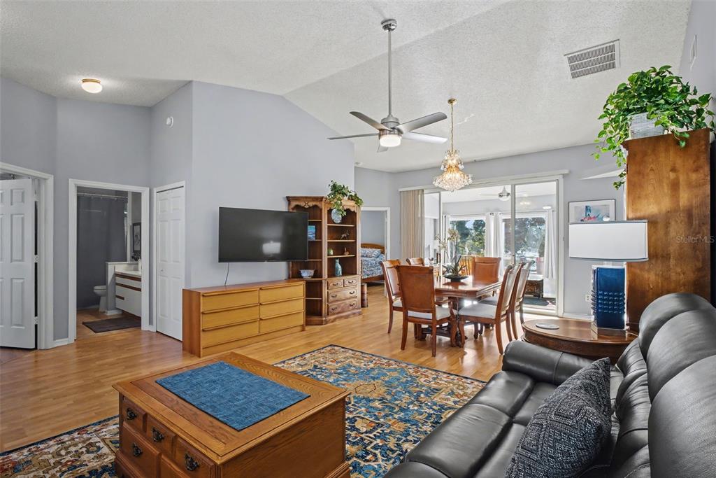 A living and dining area features hardwood floors, a vaulted ceiling, and a ceiling fan — 25049 NAVEL AVENUE, LEESBURG, FL