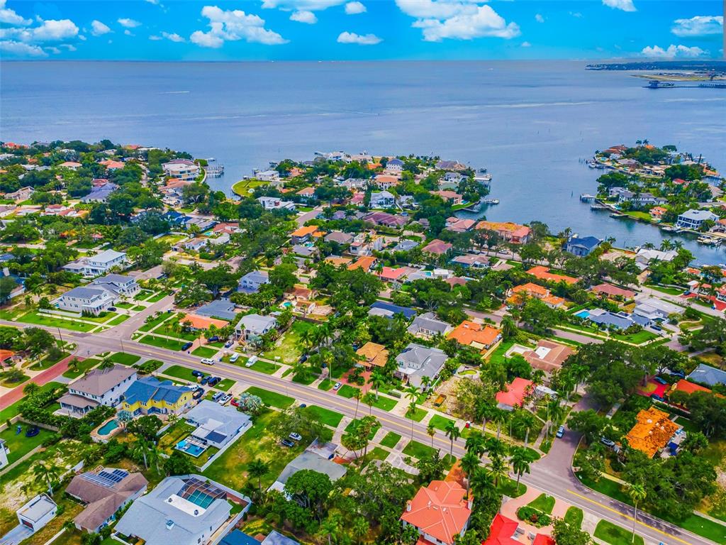 An aerial view of a coastal residential neighborhood featuring houses, lush trees, and a large bay — 910 SNELL ISLE BOULEVARD NE, ST PETERSBURG, FL