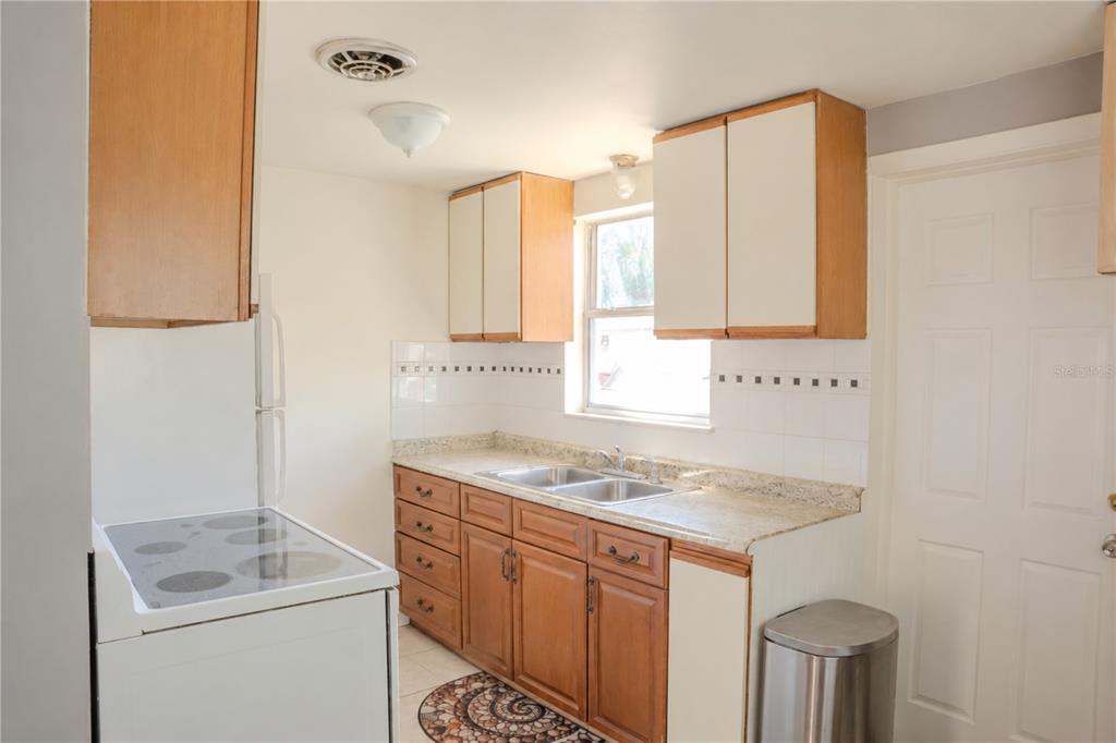 A kitchen features wood cabinets, white upper cabinets, a white stove, and a double sink — 638 DOGWOOD COURT, DUNEDIN, FL