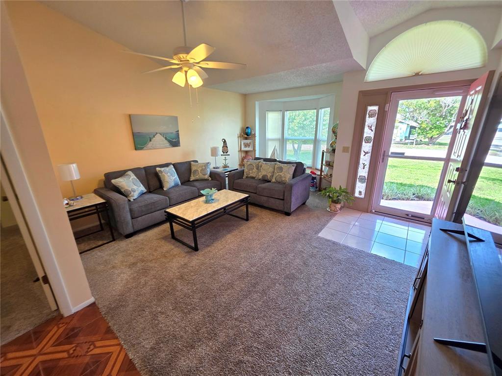 A living room features gray sofas, a marble-topped coffee table, and a front entryway door — 4164 GLADE ROAD, SPRING HILL, FL