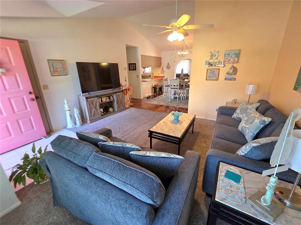 A living room features gray sofas, a coffee table, a television, and a pink door — 4164 GLADE ROAD, SPRING HILL, FL