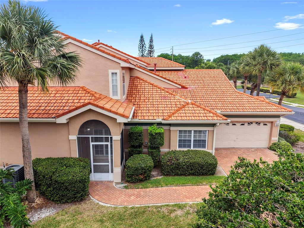 An exterior view of a two-story house with a tiled roof, garage, and brick walkway — 4850 WATERVISTA DRIVE, ORLANDO, FL
