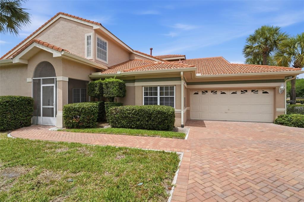 A tan house with a tile roof, brick driveway, and a screened-in front entryway — 4850 WATERVISTA DRIVE, ORLANDO, FL